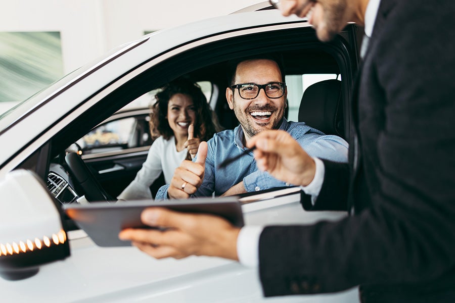 family in car with salesman signing
